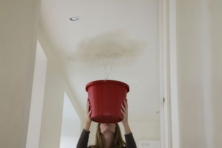 Woman trying to stop roof leak with bucket